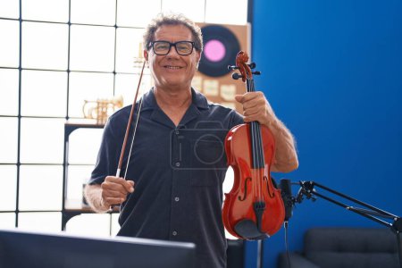 Photo for Middle age man musician smiling confident holding violin at music studio - Royalty Free Image