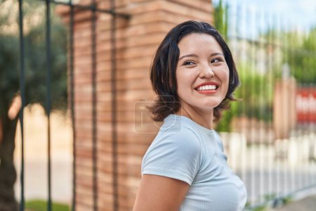 Téléchargez les photos : Jeune femme hispanique souriant confiant regardant vers le côté à la rue - en image libre de droit