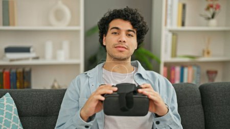 Photo for Young latin man holding virtual reality glasses at home - Royalty Free Image