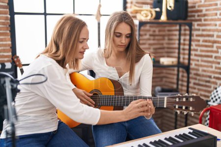 Téléchargez les photos : Deux femmes musiciens ayant des cours de guitare classique au studio de musique - en image libre de droit