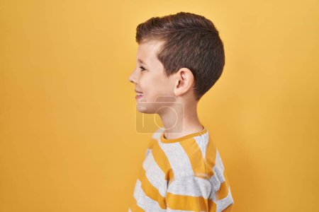 Photo for Young caucasian kid standing over yellow background looking to side, relax profile pose with natural face with confident smile. - Royalty Free Image