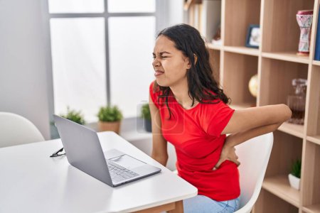 Téléchargez les photos : Jeune femme afro-américaine utilisant un ordinateur portable souffrant de maux de dos à la maison - en image libre de droit