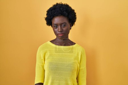 Téléchargez les photos : Jeune femme africaine debout sur jaune studio sceptique et nerveux, fronçant les sourcils bouleversés en raison de problèmes. personne négative. - en image libre de droit