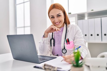 Téléchargez les photos : Jeune femme caucasienne médecin utilisant ordinateur portable écriture rapport médical à la clinique - en image libre de droit