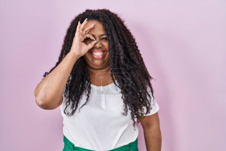 Photo for Plus size hispanic woman standing over pink background doing ok gesture with hand smiling, eye looking through fingers with happy face. - Royalty Free Image