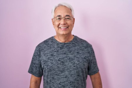 Foto de Hombre de mediana edad con el pelo gris de pie sobre el fondo rosa con una sonrisa feliz y fresca en la cara. persona afortunada. - Imagen libre de derechos