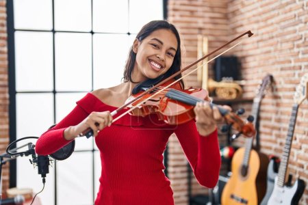 Foto de Joven mujer afroamericana músico sonriendo confiado tocando violín en el estudio de música - Imagen libre de derechos