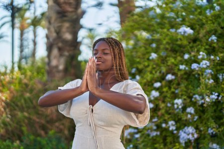 Téléchargez les photos : Femme afro-américaine priant les yeux fermés au parc - en image libre de droit