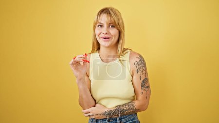Téléchargez les photos : Jeune femme blonde souriante confiante parlant sur fond jaune isolé - en image libre de droit