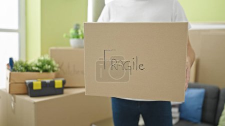 Photo for Young caucasian man holding fragile package at new home - Royalty Free Image