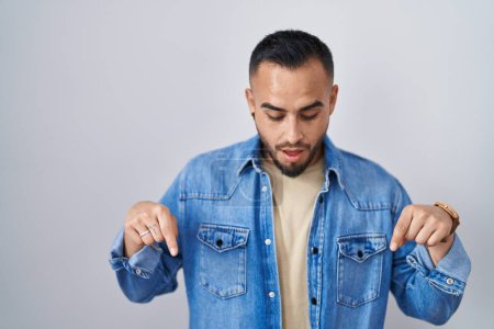 Photo for Young hispanic man standing over isolated background pointing down with fingers showing advertisement, surprised face and open mouth - Royalty Free Image