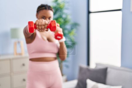 Foto de Mujer afroamericana usando pesas boxeo en casa - Imagen libre de derechos