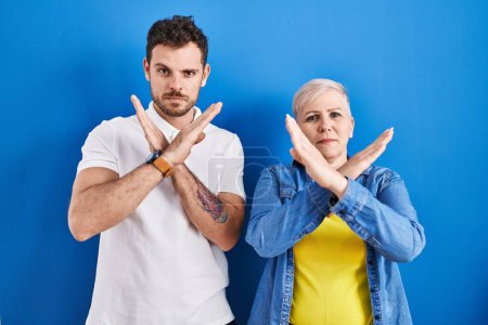 Photo for Young brazilian mother and son standing over blue background rejection expression crossing arms doing negative sign, angry face - Royalty Free Image