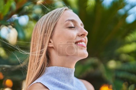 Photo for Young blonde woman breathing with closed eyes at park - Royalty Free Image