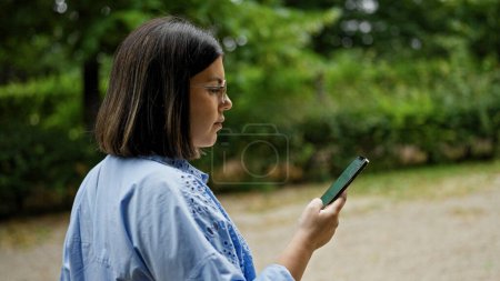 Photo for Young beautiful hispanic woman using smartphone walking at the park in Vienna - Royalty Free Image
