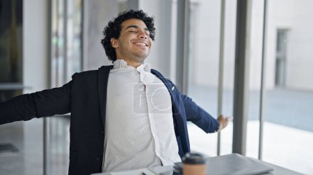 Téléchargez les photos : Jeune homme d'affaires latino-américain finition pour travailler relaxant au bureau - en image libre de droit