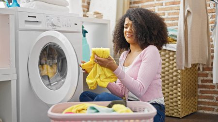 Téléchargez les photos : Femme afro-américaine laver les vêtements à la buanderie - en image libre de droit