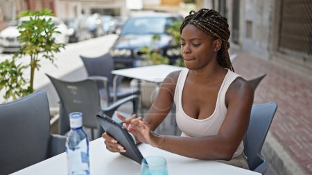 Photo for African american woman using touchpad sitting on table at coffee shop terrace - Royalty Free Image