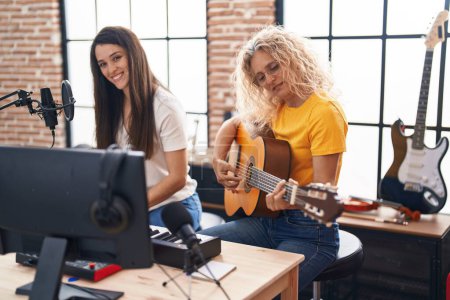 Photo for Two women musicians singing song playing classical guitar and piano at music studio - Royalty Free Image
