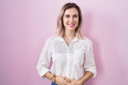 Téléchargez les photos : Young beautiful woman standing over pink background with hands together and crossed fingers smiling relaxed and cheerful. success and optimistic - en image libre de droit