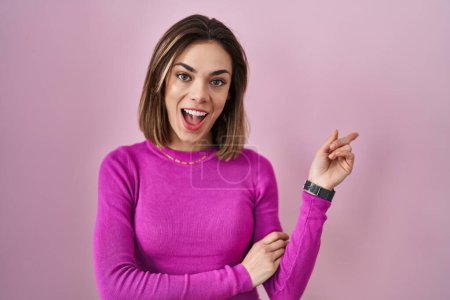 Téléchargez les photos : Hispanic woman standing over pink background with a big smile on face, pointing with hand finger to the side looking at the camera. - en image libre de droit