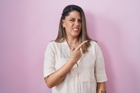 Photo for Blonde woman standing over pink background pointing aside worried and nervous with forefinger, concerned and surprised expression - Royalty Free Image