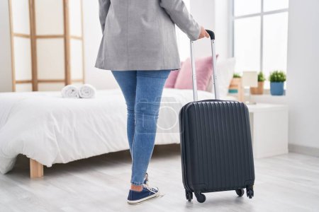 Photo for Young hispanic woman business worker holding suitcase walking at hotel room - Royalty Free Image