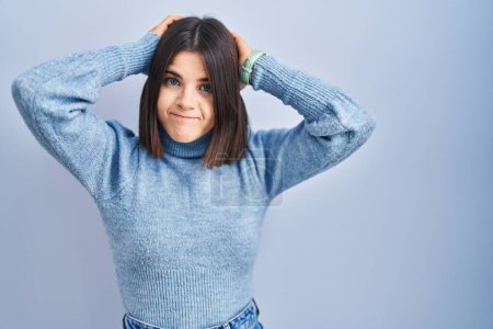 Téléchargez les photos : Young hispanic woman standing over blue background doing bunny ears gesture with hands palms looking cynical and skeptical. easter rabbit concept. - en image libre de droit