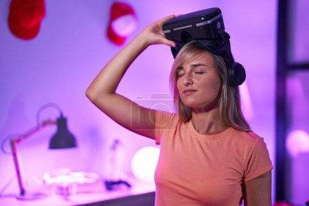 Téléchargez les photos : Jeune femme blonde streamer portant des lunettes de réalité virtuelle à la salle de jeux - en image libre de droit