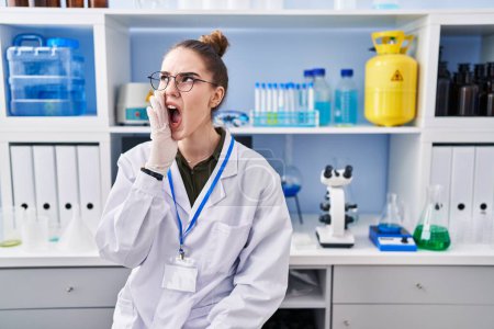Photo for Young hispanic girl working at scientist laboratory clueless and confused with open arms, no idea and doubtful face. - Royalty Free Image