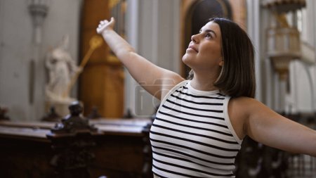 Foto de Joven mujer hispana hermosa visitando la iglesia con los brazos abiertos en la iglesia agustiniana en Viena - Imagen libre de derechos