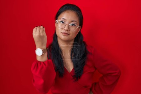 Foto de Mujer joven asiática de pie sobre fondo rojo haciendo gesto italiano con la mano y los dedos expresión confiada - Imagen libre de derechos