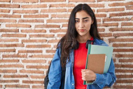 Photo for Young teenager girl wearing student backpack and holding books thinking attitude and sober expression looking self confident - Royalty Free Image