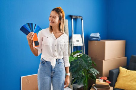 Photo for Young hispanic woman smiling confident choosing paint color at new home - Royalty Free Image