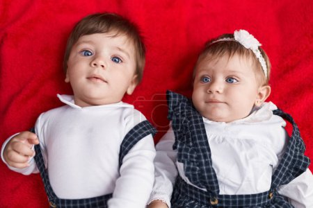 Photo for Two adorable babies lying on sofa over isolated red background - Royalty Free Image
