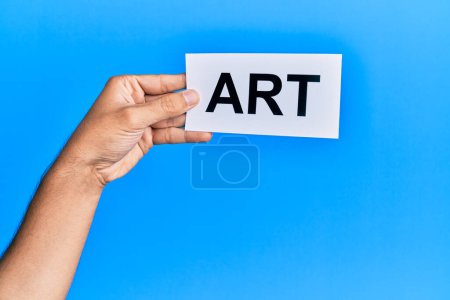 Photo for Hand of caucasian man holding paper with art word over isolated blue background - Royalty Free Image
