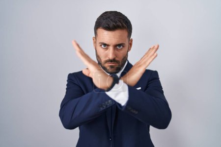 Foto de Hombre hispano guapo usando traje y expresión de rechazo de corbata cruzando brazos haciendo signo negativo, cara enojada - Imagen libre de derechos