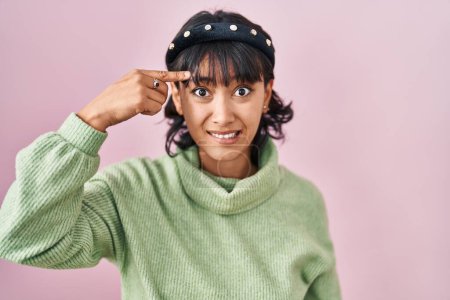 Téléchargez les photos : Young beautiful woman standing over pink background pointing unhappy to pimple on forehead, ugly infection of blackhead. acne and skin problem - en image libre de droit