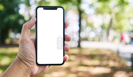 Foto de Hombre sosteniendo teléfono inteligente que muestra la pantalla en blanco blanco en el parque - Imagen libre de derechos