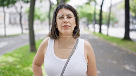 Photo for Young beautiful hispanic woman standing with serious expression at the park in Vienna - Royalty Free Image