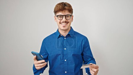 Téléchargez les photos : Jeune homme hispanique utilisant smartphone et carte de crédit sur fond blanc isolé - en image libre de droit