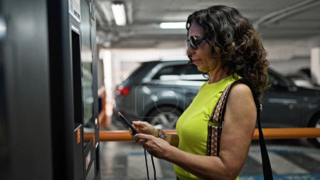 Téléchargez les photos : Moyen Age femme hispanique payer au parking de la machine - en image libre de droit