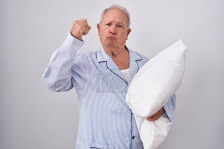 Photo for Senior man with grey hair wearing pijama hugging pillow strong person showing arm muscle, confident and proud of power - Royalty Free Image