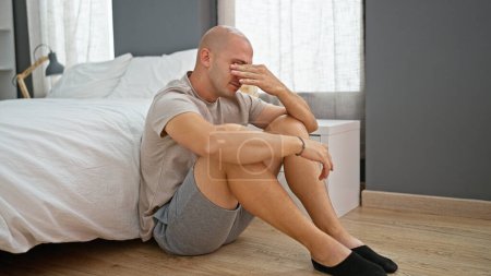 Photo for Young hispanic man stressed sitting on floor at bedroom - Royalty Free Image