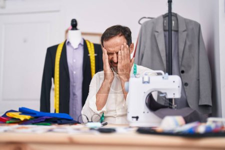 Photo for Middle age man tailor stressed using sewing machine at tailor shop - Royalty Free Image