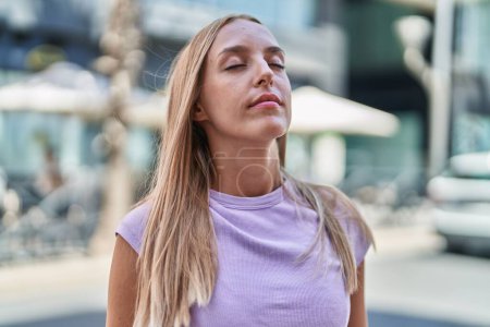 Téléchargez les photos : Young blonde woman breathing with closed eyes at street - en image libre de droit