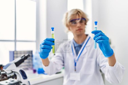 Téléchargez les photos : Jeune homme blond scientifique tenant des éprouvettes en laboratoire - en image libre de droit