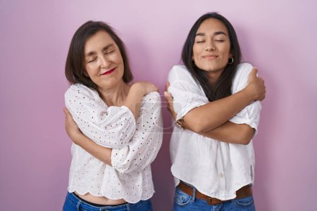 Photo for Hispanic mother and daughter together hugging oneself happy and positive, smiling confident. self love and self care - Royalty Free Image