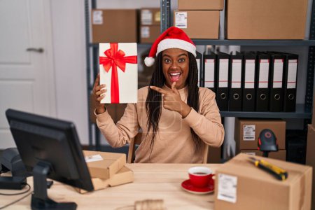 Téléchargez les photos : Jeune afro-américain avec des tresses travaillant dans une petite entreprise e-commerce à Noël souriant heureux pointant avec la main et le doigt - en image libre de droit