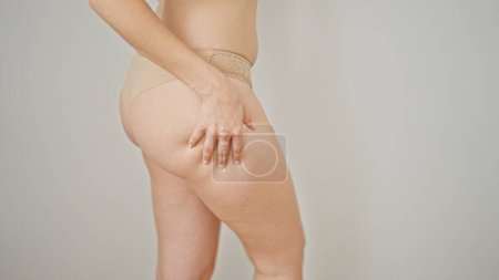 Foto de Young redhead woman wearing lingerie touching cellulitis on ass over isolated white background - Imagen libre de derechos